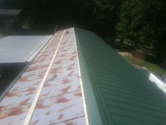 Old rusted panels beside newly installed green metal roofing — Wind Damage Roof Repair by Roofing Brothers in Hartford